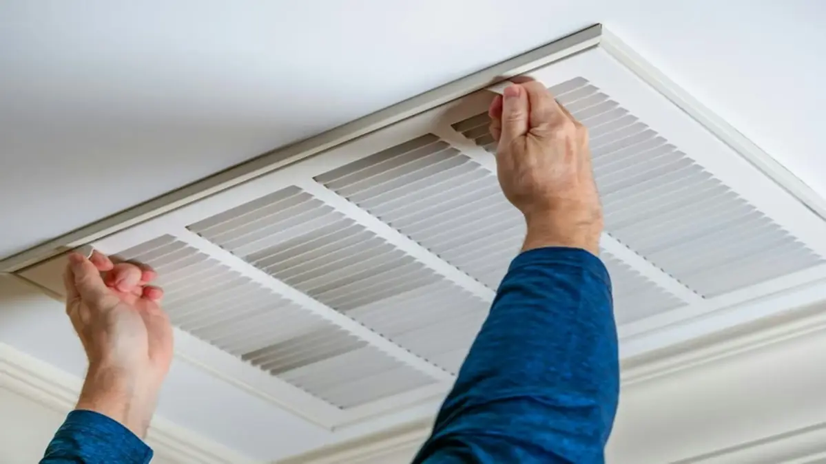 Le technicien en train de fermer la grille de la climatisation au plafond